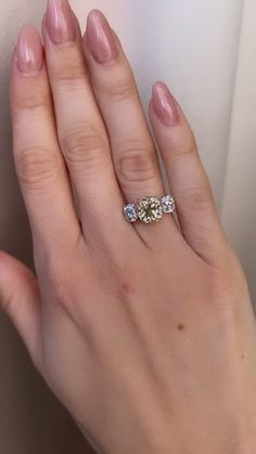 a woman's hand with three diamond rings on her left and the other hand holding an engagement ring