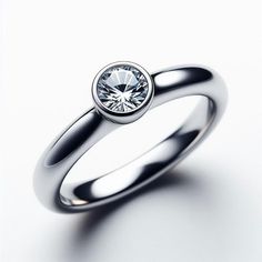 a white gold ring with a round brilliant cut diamond in the center, on a plain surface