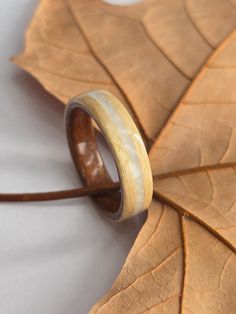 Immerse yourself in the tranquil embrace of nature's whispers with our "Luna Forest" This exquisite piece is meticulously crafted from light maple wood on the outside, dark rich brown walnut wood on the inside, and features a stunning 3mm thick inlay of crushed white moonstones that gracefully encircle the ring. The light maple wood provides a beautiful contrast to the deep, earthy tones of the walnut wood liner, evoking the tranquil harmony found in nature. The crushed white moonstones add a touch of celestial beauty, capturing the ethereal glow of moonlit nights. With a glossy finish that not only enhances its natural beauty but also offers waterproof protection and resistance to scratches, this ring is designed to be as durable as it is beautiful. Each ring is a unique piece of art, ref Nature-inspired White Jewelry For Weddings, Nature-inspired White Jewelry For Wedding, Artisan White Ring For Wedding, Nature-inspired White Wedding Jewelry, Nature-inspired Round Natural Jewelry, Natural Color Nature-inspired Round Jewelry, Adjustable White Nature-inspired Rings, Outside Dark, Unique Wedding Band