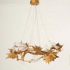 a chandelier hanging from the ceiling with leaves and acrylic crystals on it