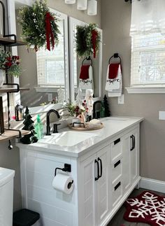 a bathroom decorated for christmas with wreaths on the window sill and other decorations