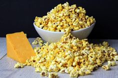 corn kernels and butter on a wooden table next to a white bowl with a block of butter