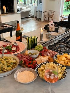 a table filled with plates and bowls of food next to wine glasses on top of a counter