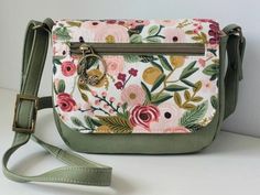 a floral purse is sitting on a white table with a green strap around the shoulder