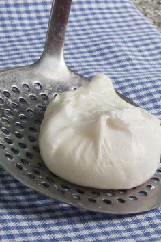 a close up of a spoon with some food on it near a blue and white checkered table cloth