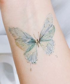 a white butterfly tattoo on the arm