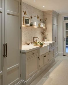 a kitchen with white cabinets and gold faucets