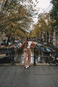 a woman standing on a bridge next to a body of water