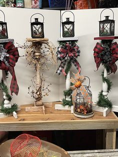 christmas decorations are displayed on a table in front of a wall with hanging lanterns and wreaths