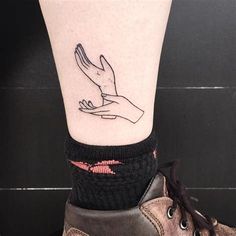 a small tattoo on the ankle of a person's foot with a hand holding a dove