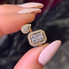 a woman's hand holding an engagement ring with two square shaped diamonds on it