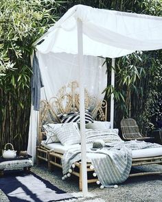 an outdoor bed made out of pallet wood with white canopy and pillows on it