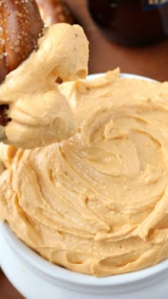 a white bowl filled with peanut butter next to pretzels