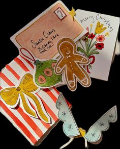 some cards are laying on top of each other and decorated with paper flowers, butterflies, and gingerbreads