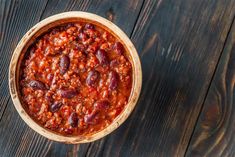 a bowl filled with chili sitting on top of a wooden table