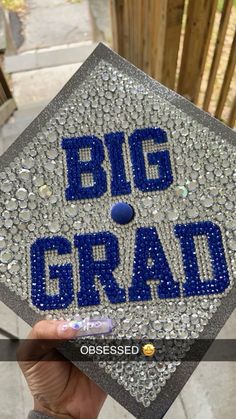 someone holding up a graduation cap with the words big grad in blue on it