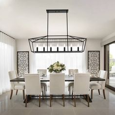 a dining room table with white chairs and a chandelier