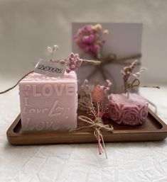 two soaps on a tray with flowers and a card in the background that says love