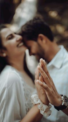 a man and woman holding each other close to their face while they are touching hands