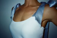 a woman wearing a white top with a blue bow around her neck