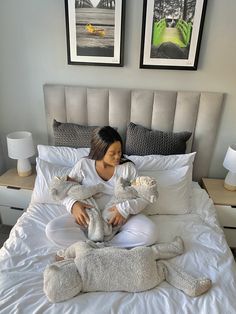 a woman sitting on top of a bed holding two stuffed animals