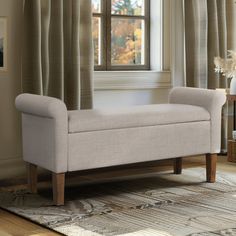 a white bench sitting in front of a window next to a rug on top of a wooden floor