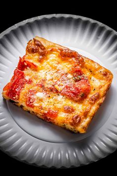 a piece of pizza on a white plate with cheese and tomato toppings in the middle