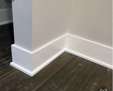 the corner of an empty room with wood flooring