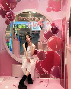 a woman sitting in front of a mirror with hearts on the wall and balloons hanging from it