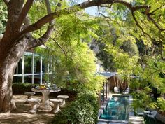 an outdoor dining area with tables and chairs next to a pool surrounded by greenery