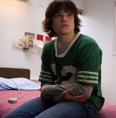 a young man sitting on top of a bed