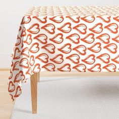 an orange and white tablecloth with hearts on it in front of a wooden chair