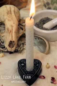 a lit candle sitting on top of a table next to some dried flowers and other items