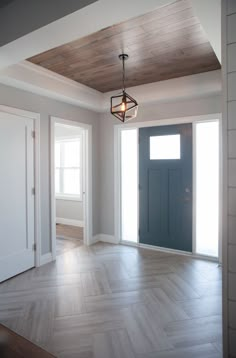 an empty room with a blue door and light fixture hanging from the rafter ceiling