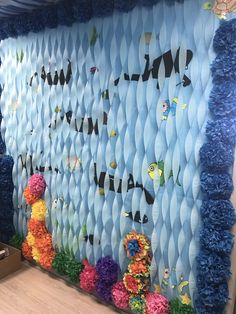 the wall is decorated with paper flowers and pom poms