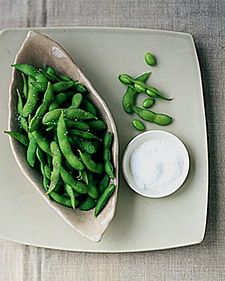 green beans are on a plate next to a small bowl with some white substance in it