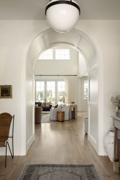 an archway leads to the living room and dining area in this house with white walls