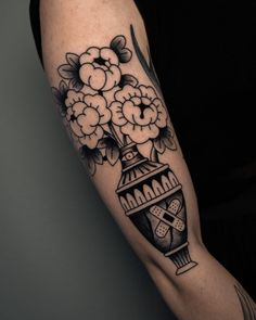 a black and white flower vase tattoo on the arm