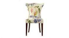 an upholstered chair with floral fabric and wooden legs, against a white background