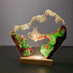 a glass display with a totoro on it's face and trees in the background