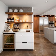 a kitchen with open shelving and wine bottles on the counter top, along with an oven