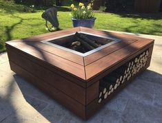 a fire pit sitting on top of a patio next to a grass covered park area