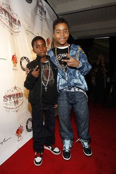 two young men standing next to each other on a red carpet