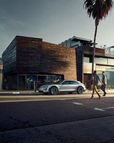 two people crossing the street in front of a building with a palm tree on it