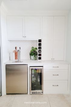 a kitchen with white cabinets and stainless steel refrigerator freezer combo in the center, built - in wine rack on the wall