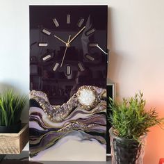 a clock that is on the side of a table next to some potted plants