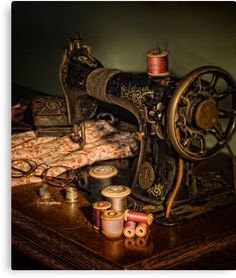 an old sewing machine sitting on top of a table next to some spools of thread