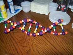 a wooden table topped with lots of colorful beads and plastic candy sticks on top of it