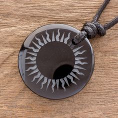 Carry the magic of a solar eclipse with you always with this black jade pendant necklace. Jorge Lopez of Guatemala handcrafts this necklace by carving the rays of the sun on the round smooth jade he suspends from black waxed cotton cord with an adjustable sliding knot. Adjustable Round Carved Necklaces, Adjustable Carved Round Necklace, Adjustable Carved Round Necklaces, Black Necklace With Sun And Moon Design As Gift, Adjustable Black Medallion Jewelry, Adjustable Black Medallion Necklace, Black Carved Round Jewelry, Adjustable Black Carved Necklace, Jade Amulet Necklace With Round Pendant