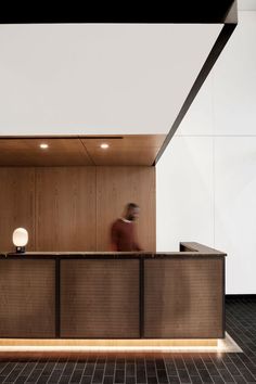 a person sitting at a desk in front of a wall with wooden paneling on it